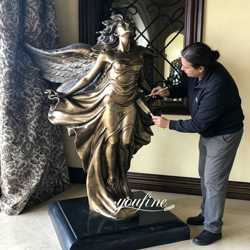 A person is maintaining an indoor bronze angel statue