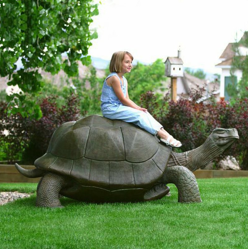 A child is sitting on a bronze turtle sculpture