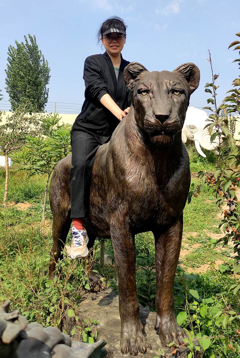 A YouFine employee is sitting on a bronze lioness sculpture